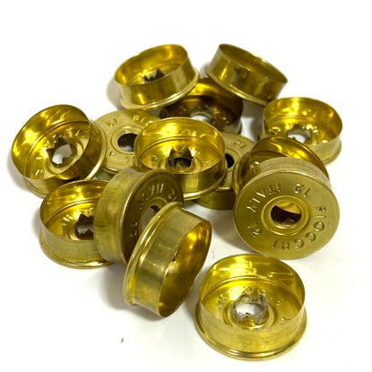 Pile of gold Fiocchi 12 gauge casing bottoms deprimed viewed from the inside, showing primer holes.
