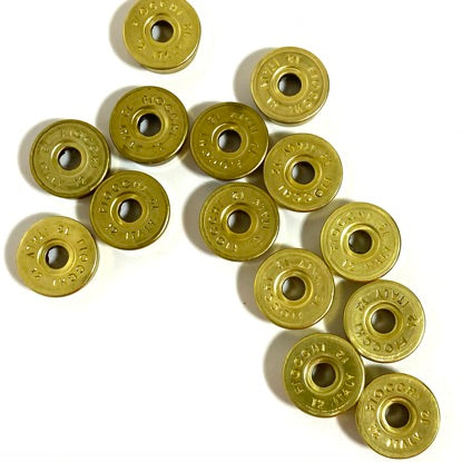 Gold Fiocchi deprimed 12 gauge shotgun shell bottoms arranged in a diagonal line on a white background.