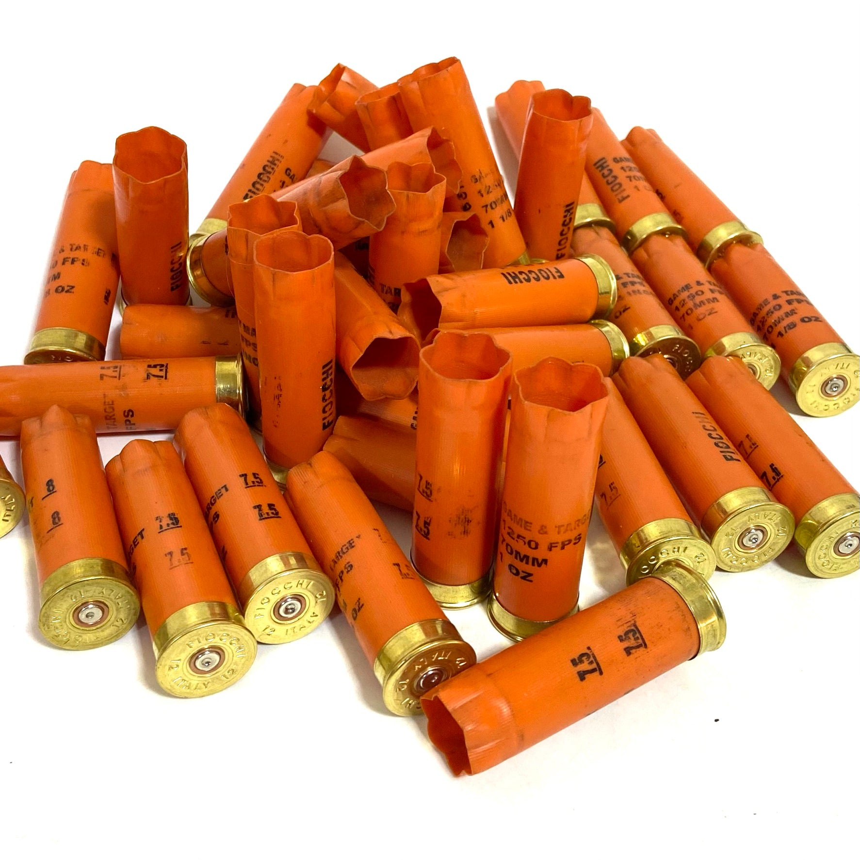 A large pile of orange Fiocchi casings heaped together, showing gold bases and open crimped ends.