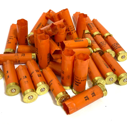 A large pile of orange Fiocchi casings heaped together, showing gold bases and open crimped ends.