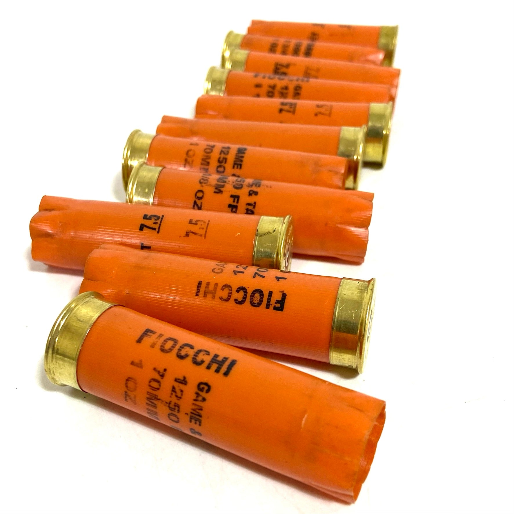 Eight orange Fiocchi casings lined up diagonally, showing gold rims and stamped Fiocchi text.