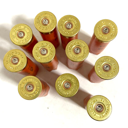 Ten orange Fiocchi 12 gauge hulls viewed from above, showing gold headstamps and fired primers.