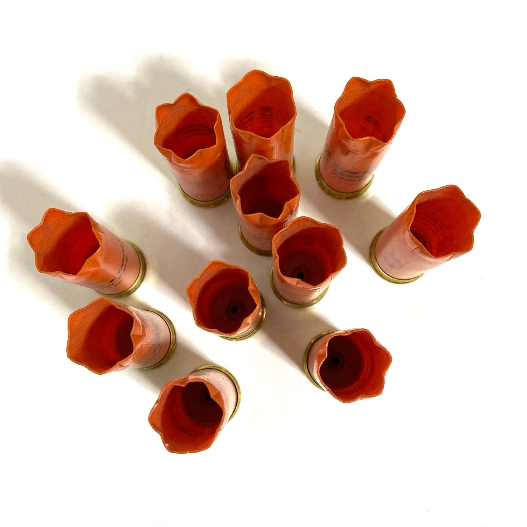 Ten orange Fiocchi shells viewed from above, showing open crimped mouths and hollow empty interiors.