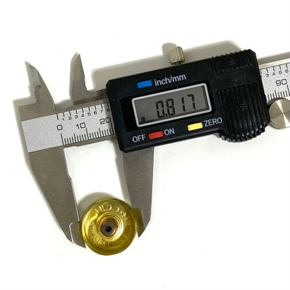 A digital caliper measuring a gold 12 gauge shotgun shell headstamp, showing a reading of 0.817 inches.

