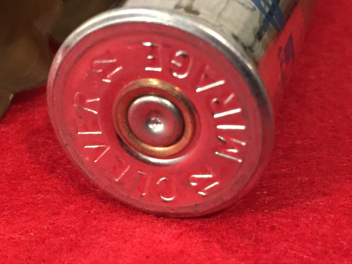 Close-up of a red shotgun shell silver base embossed "Clever Mirage" on red fabric