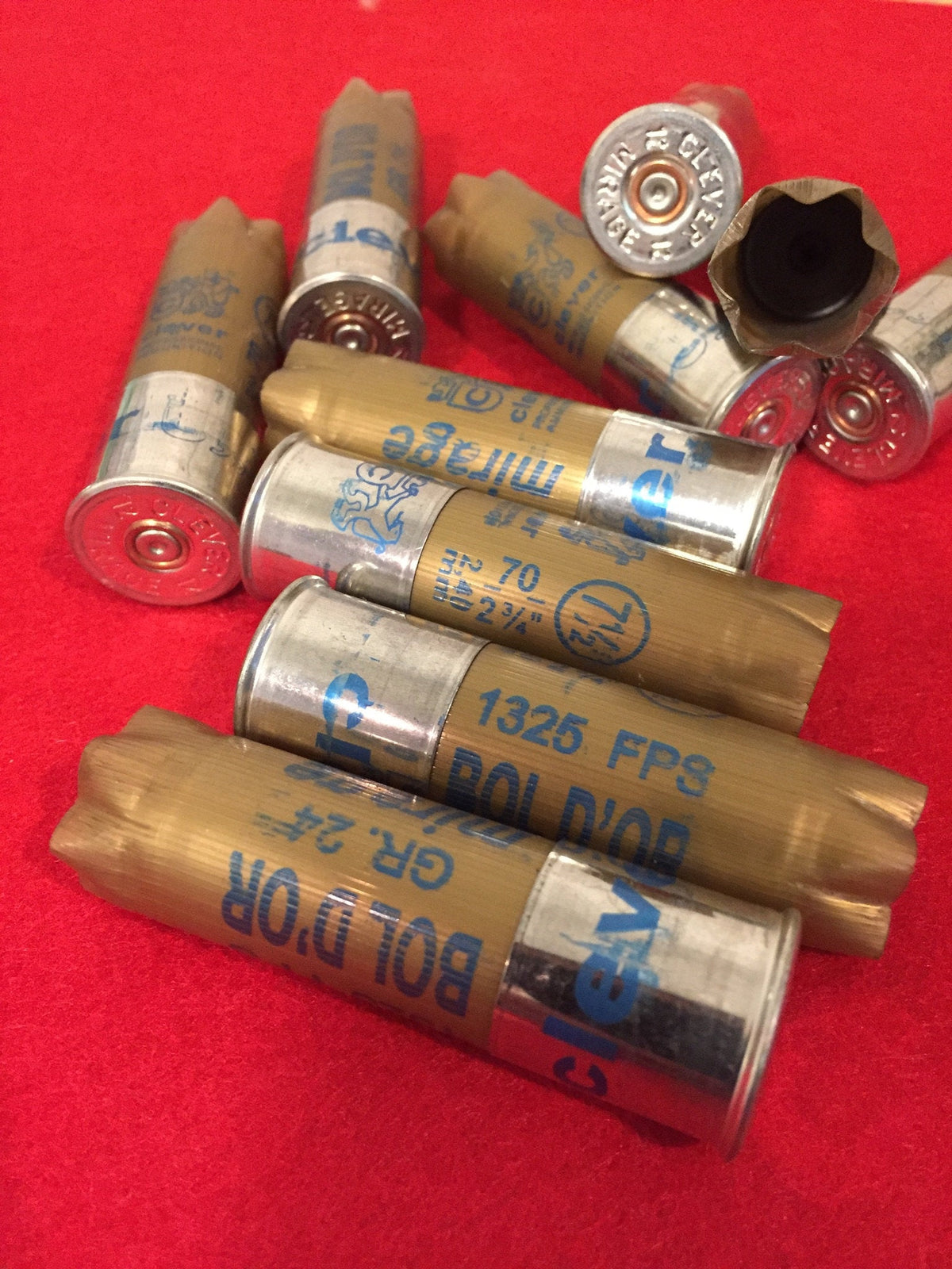 Pile of gold shotgun shells with silver bases printed "Bol D'Or", "1325 FPS", "GR.24" on red fabric, one shell showing black wadding inside