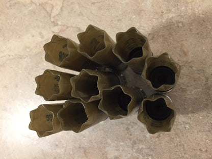 Gold shotgun shells viewed from above showing open star-crimped mouths on a stone surface