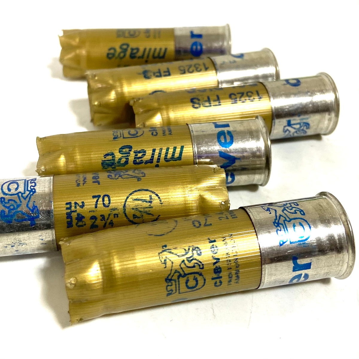 5 gold shotgun shells with silver bases lying at angles printed "mirage", "Bol D'Or", "1325 FPS", "clever" text