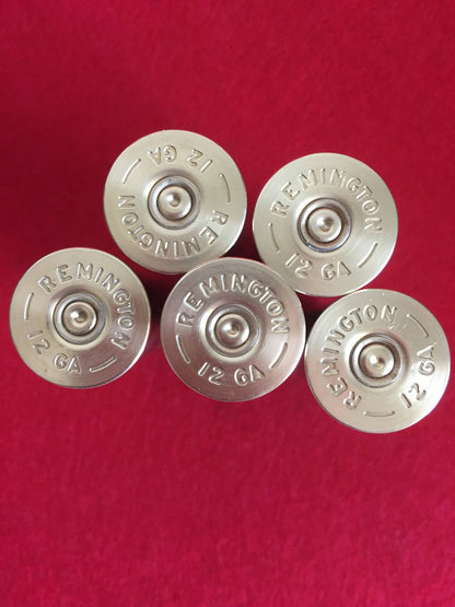 5 silver brass heads of Remington 12 gauge shotgun shells viewed from above on a red surface