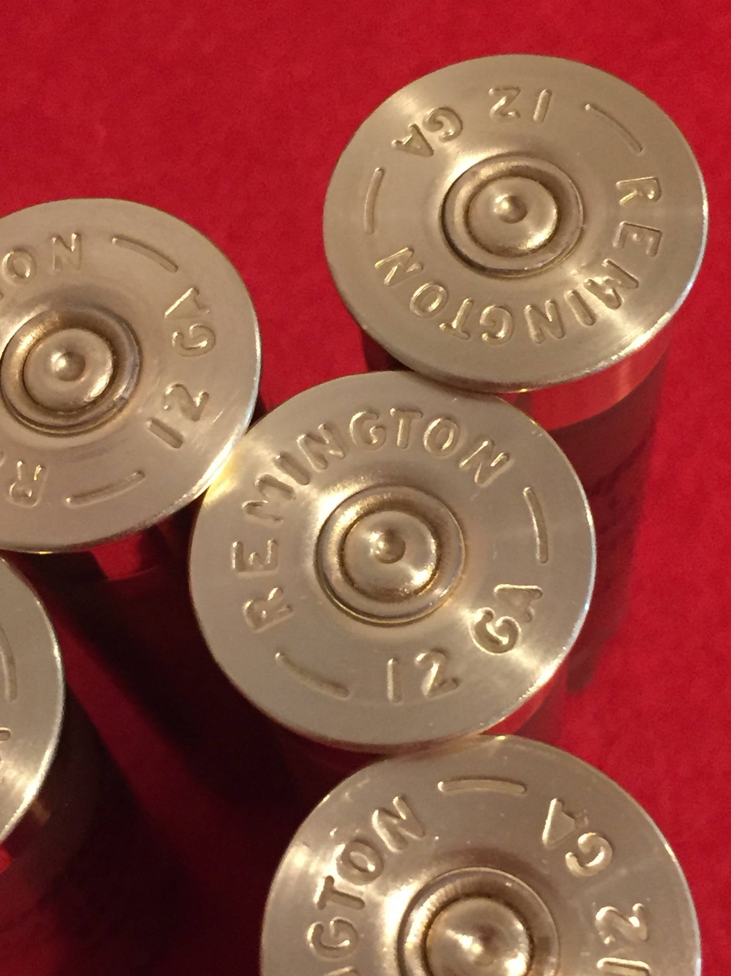 Close-up of gold brass heads of Remington 12 gauge shotgun shells on a red surface