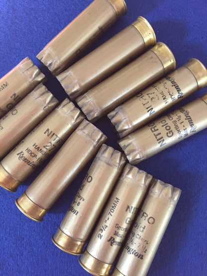 Gold Remington Nitro shotgun shells fanned out on a blue background, showing star-crimped tops and printed load markings