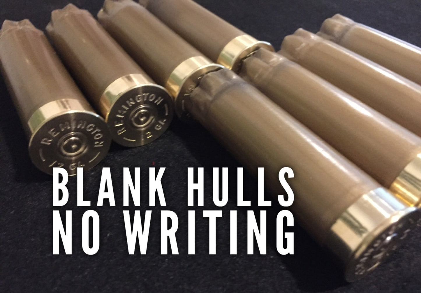 Six gold 12 gauge shotgun hulls on dark surface with REMINGTON headstamps and white BLANK HULLS NO WRITING text overlay.