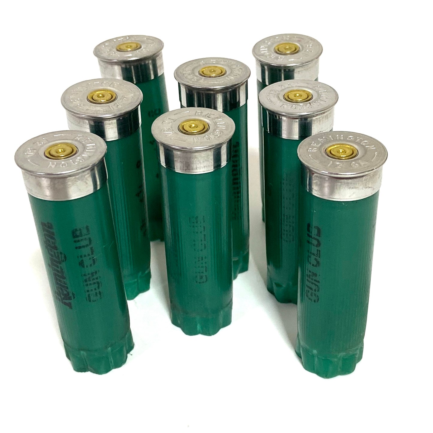 Seven empty green 12ga Remington Gun Club shells standing upright with silver bases and gold primers showing