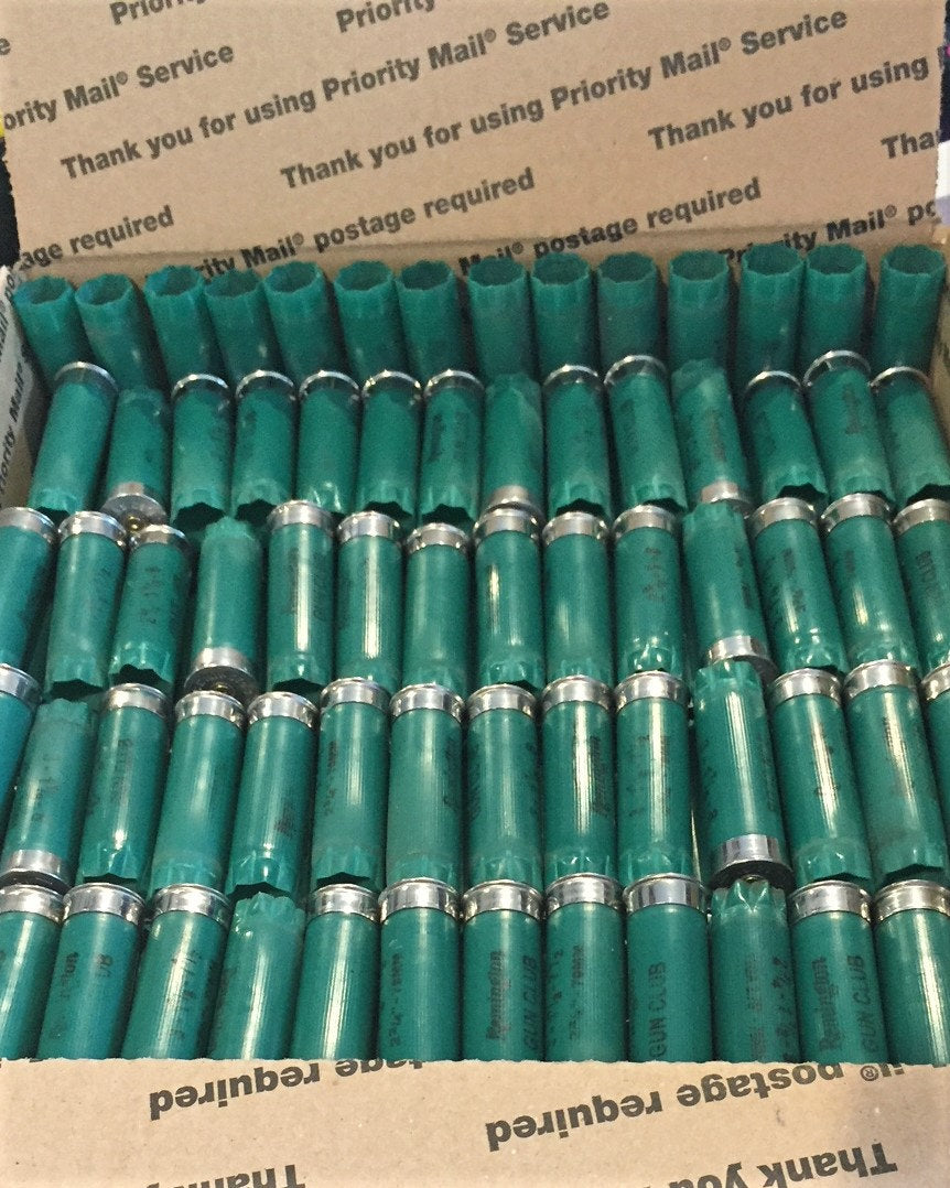 Rows of once-fired green 12ga Remington Gun Club casings packed neatly in a Priority Mail shipping box
