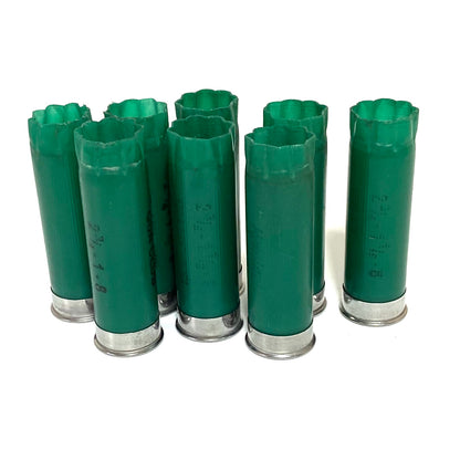 Seven spent green 12ga Remington Gun Club shells standing together with open crimped tops and silver bases