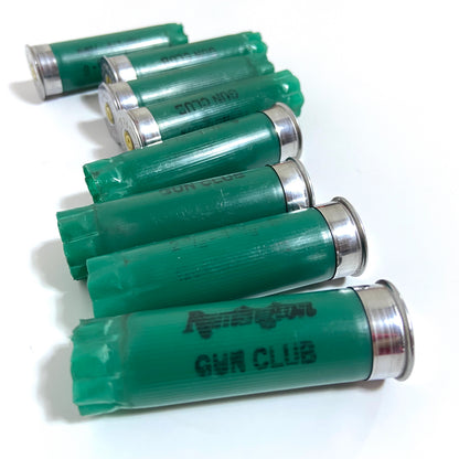Seven spent green 12ga Remington Gun Club cartridges arranged diagonally with GUN CLUB text visible