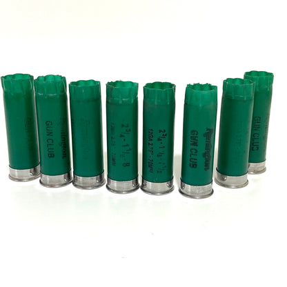 Eight used green 12ga Remington Gun Club casings standing in a front row with GUN CLUB markings