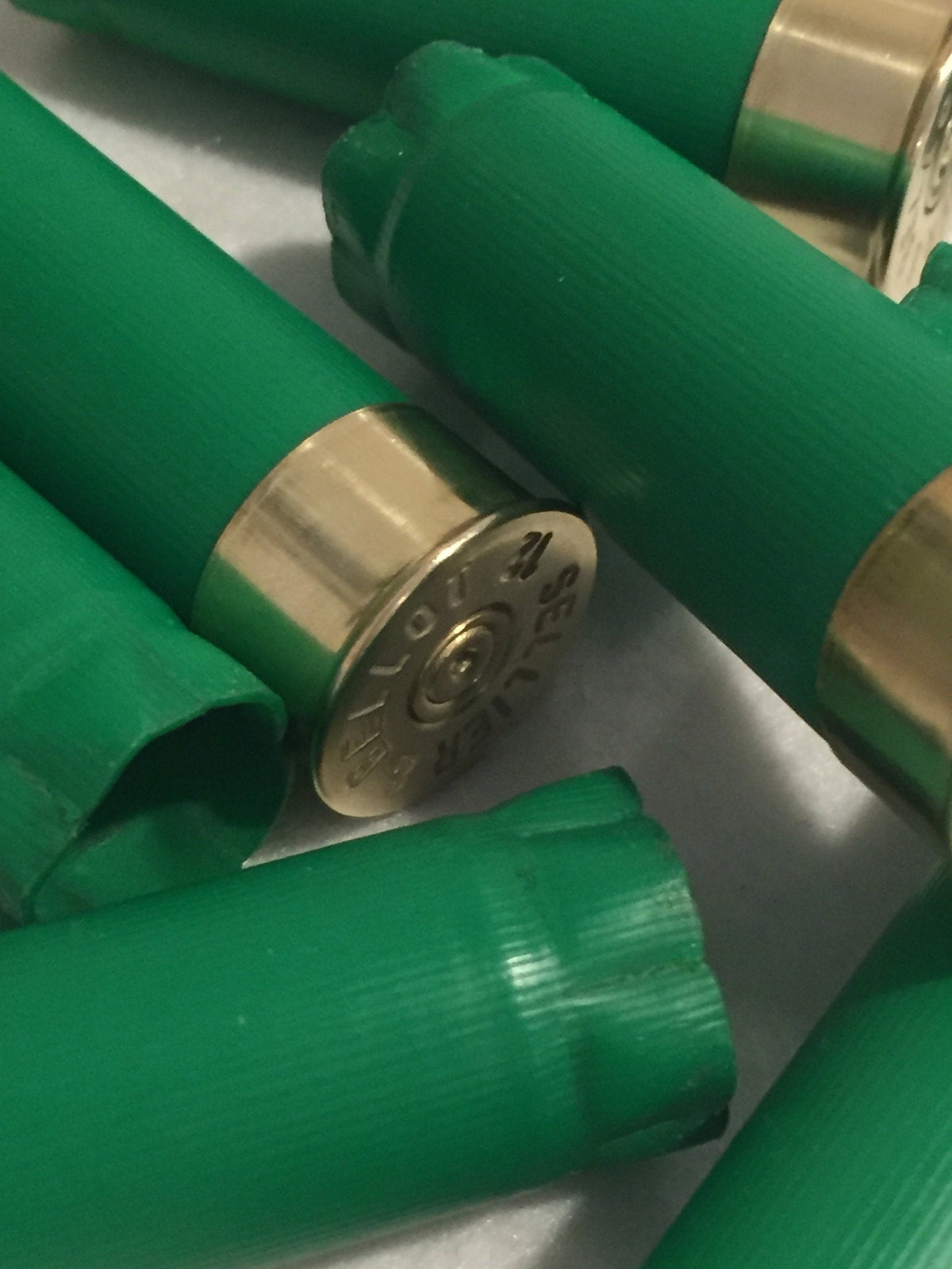 Green shotgun shells with a gold brass head close-up showing Sellier and Bellot headstamp text