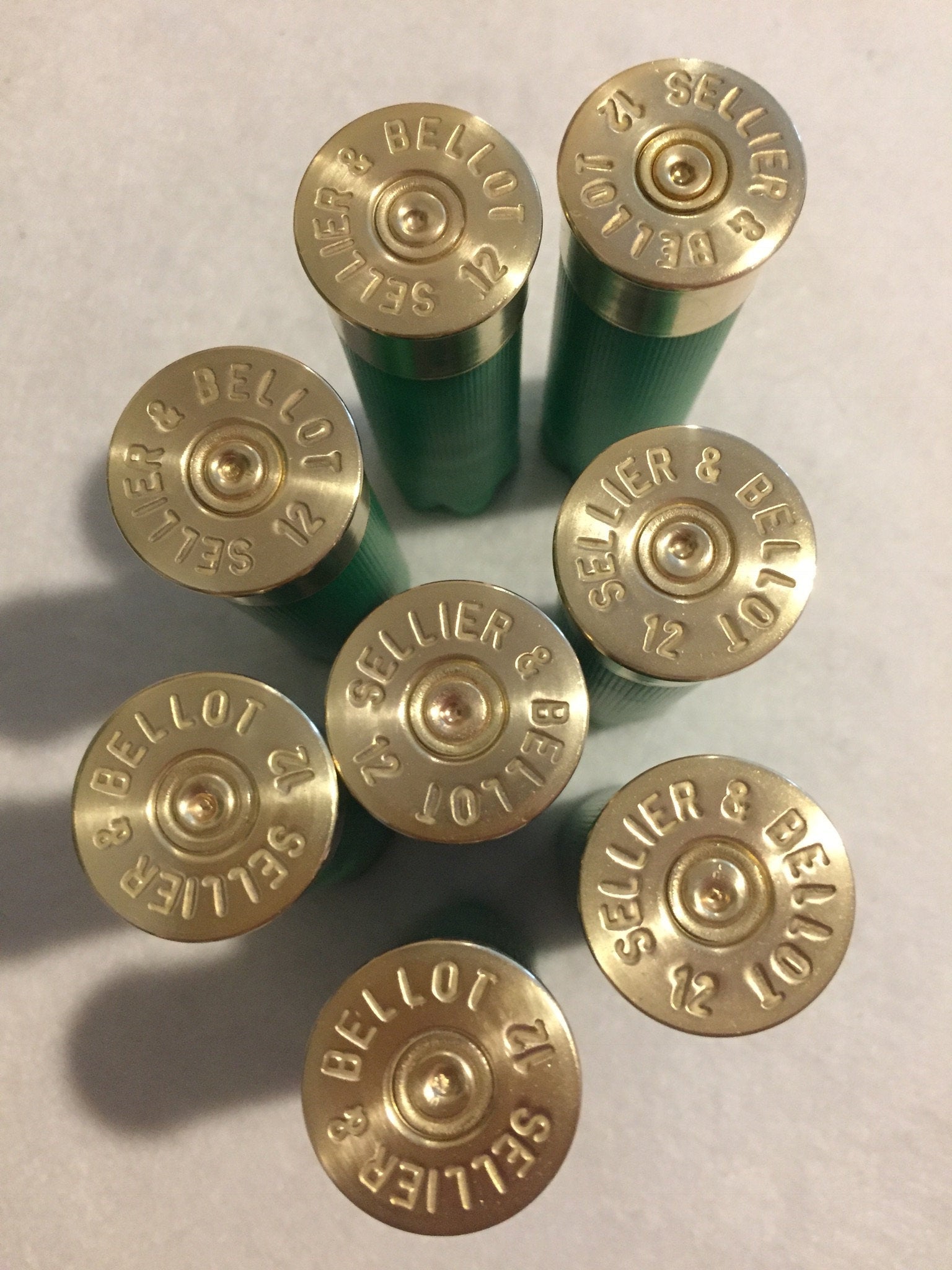 8 gold brass heads of green Sellier and Bellot 12 gauge shotgun shells viewed from above showing headstamp text