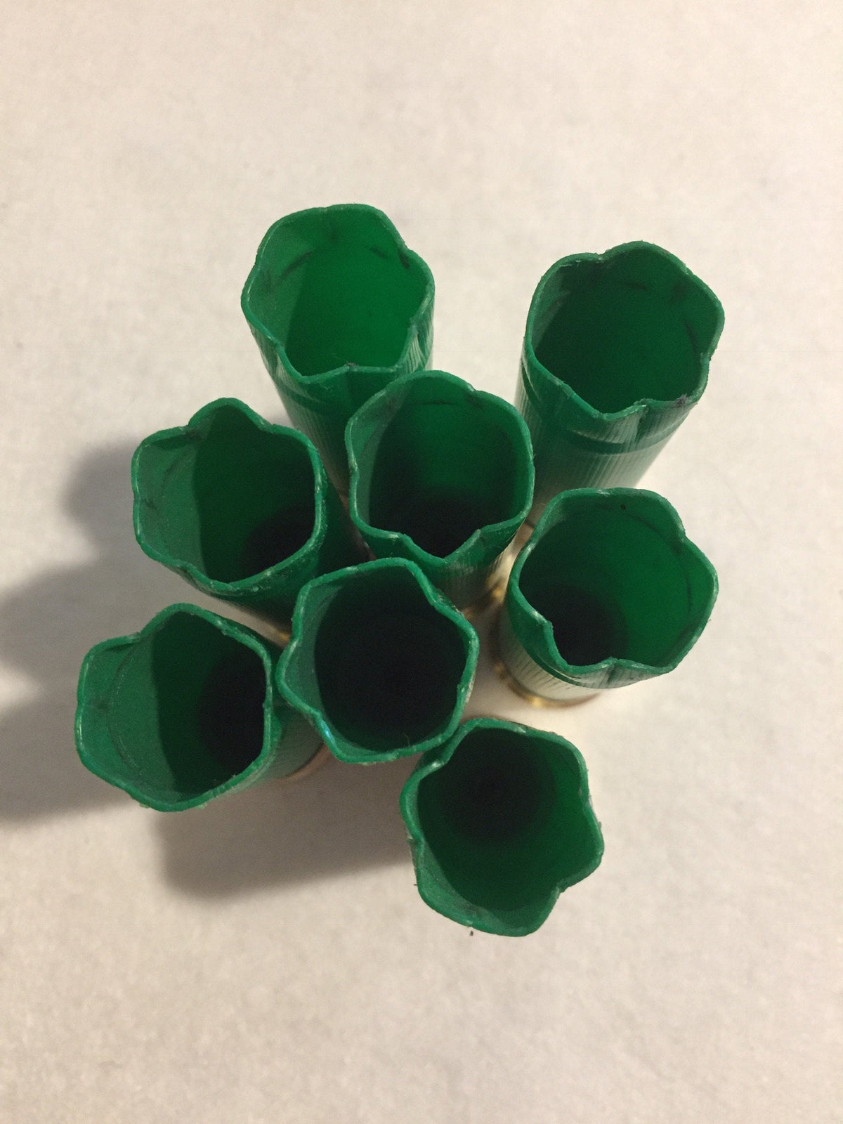 7 open mouths of green shotgun shells viewed from above in a cluster