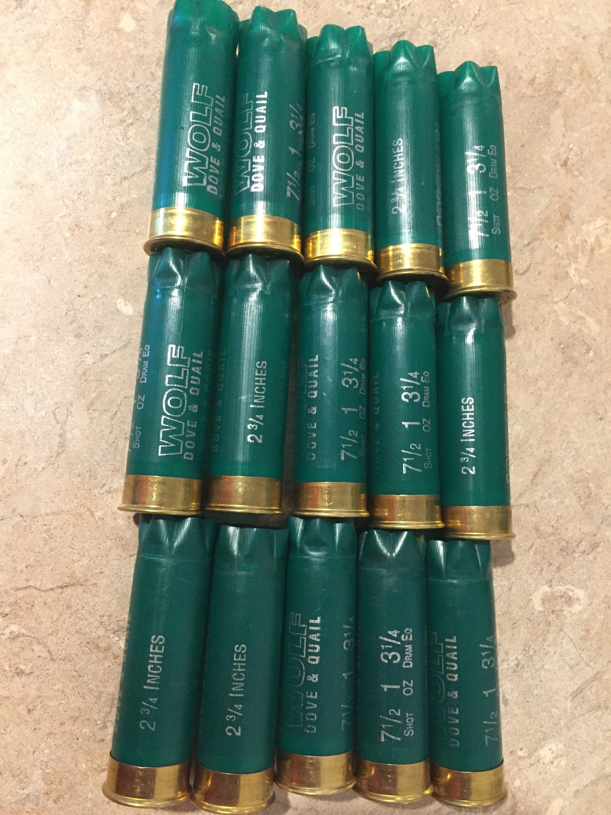 15 green shotgun shells with brass bases arranged in rows printed "Wolf Dove & Quail" and "2¾ Inches"
