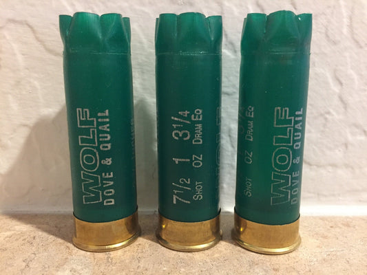 3 green shotgun shells with brass bases standing upright printed "Wolf Dove & Quail", "7½", "1", "3¼", "Shot Oz Dram Eq"