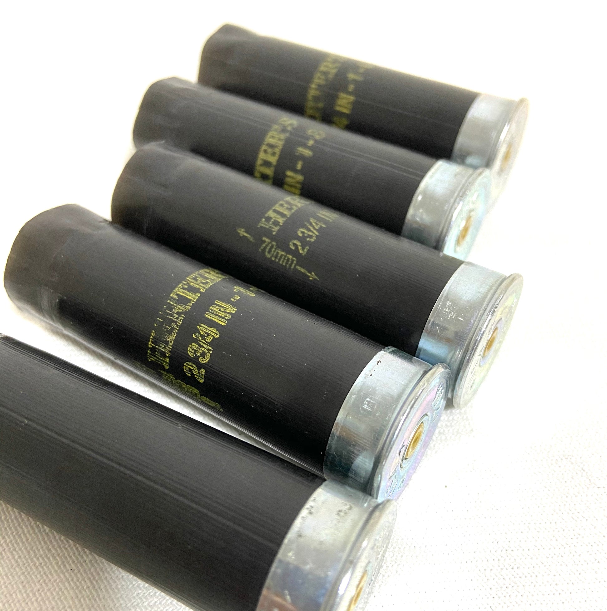 Close-up of inert black plastic shotgun hulls featuring classic gold Herter's print and silver-toned metal bottoms.