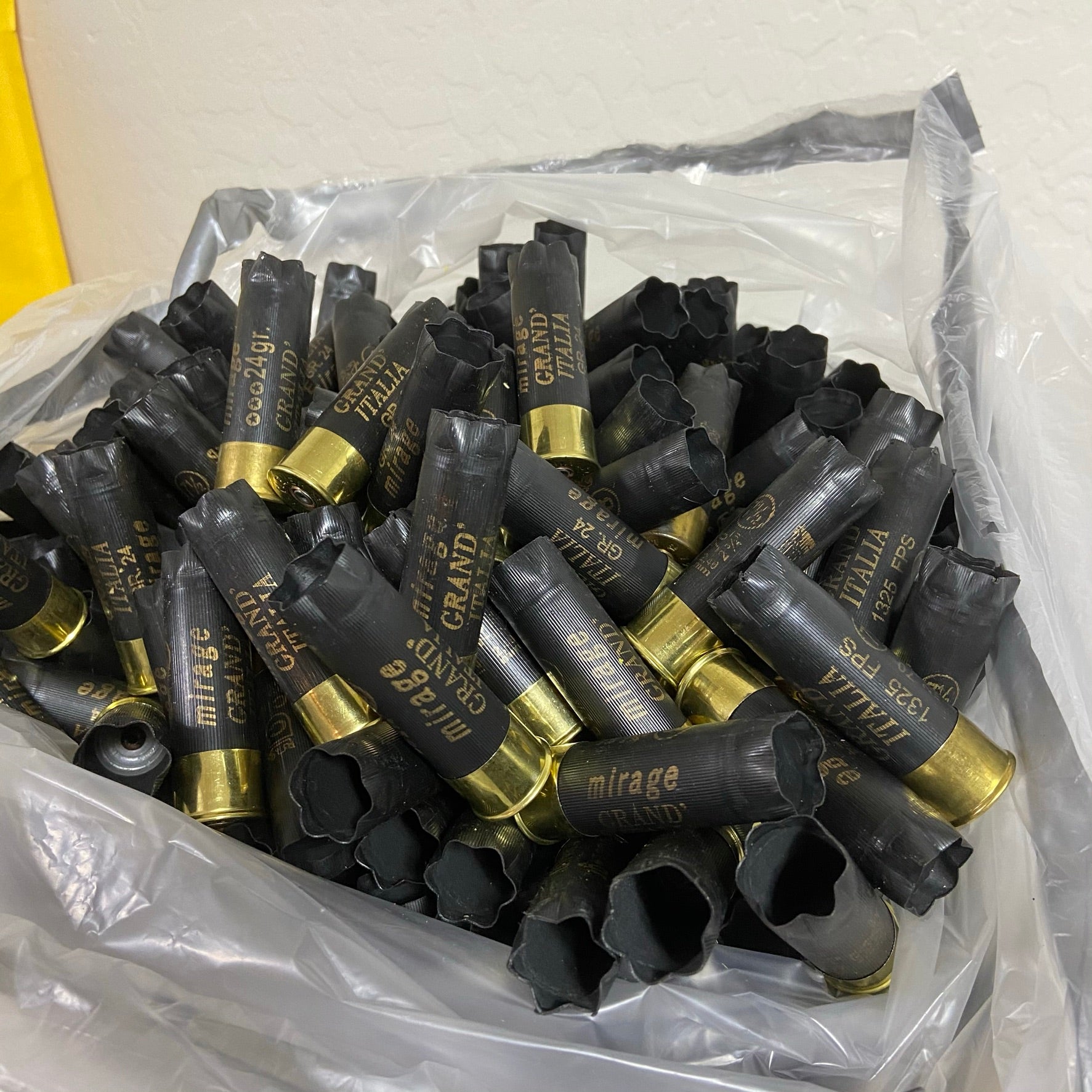 Bulk pile of black “Mirage Grand Italia” 12 gauge shotgun shells with brass bases in a clear plastic bag