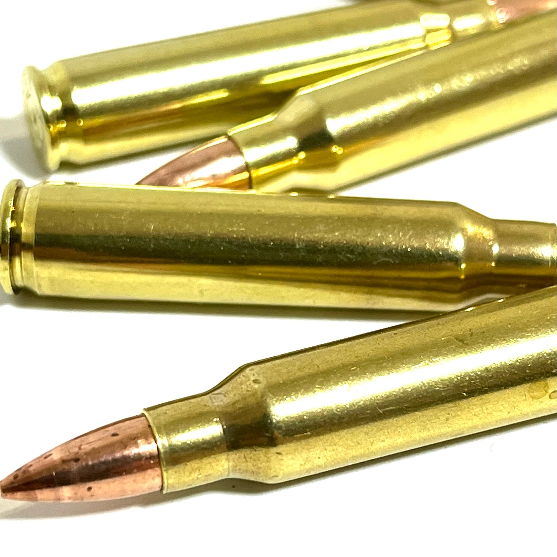 Close-up view of shiny brass inert 223 rounds lying horizontally on a clean surface for film props.