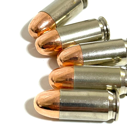 A close up view of five nickel 45 ACP dummy rounds with copper round nose bullets stacked on a white background.