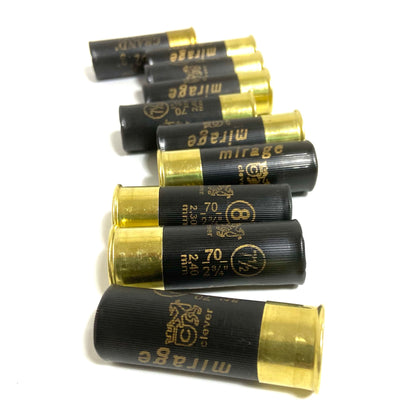 A stack of ten black inert dummy shotgun shells with shiny brass bottoms arranged horizontally on a white background.