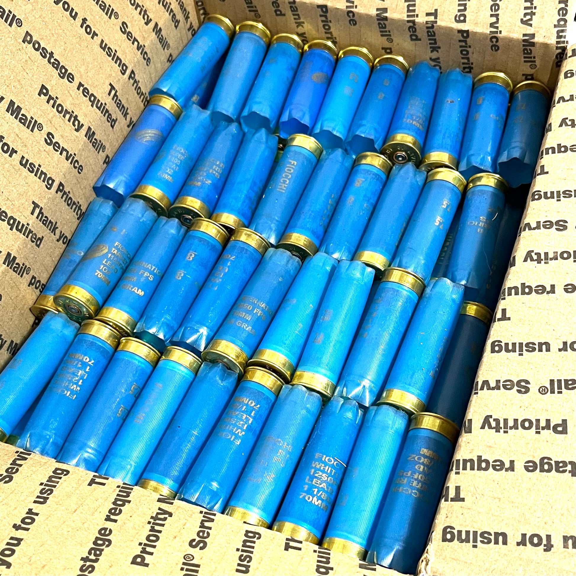 Rows of light blue Fiocchi 12 gauge empty shotgun shells packed inside a cardboard shipping box