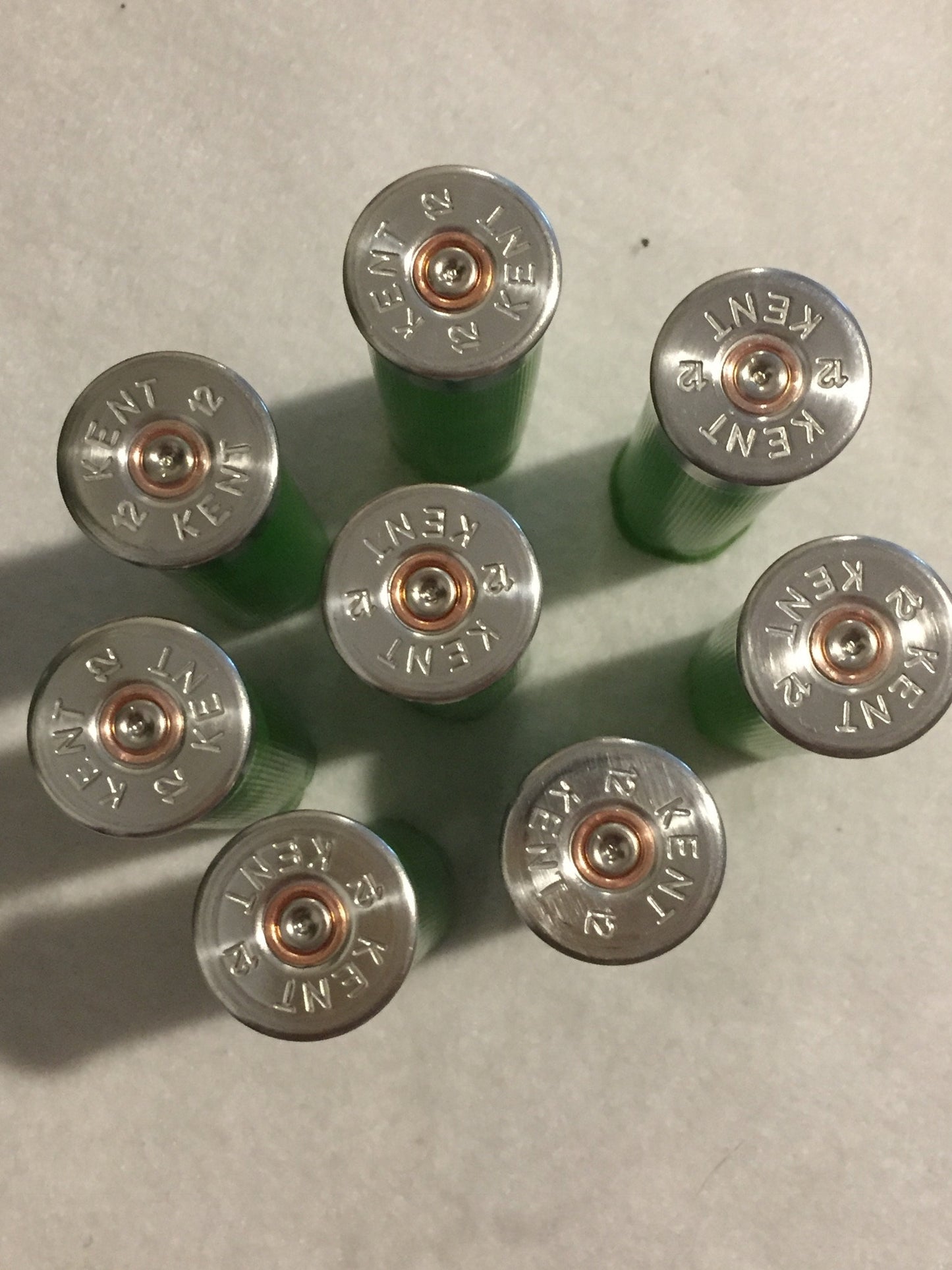 7 empty lime green 12 gauge shotgun shells viewed from above showing silver Kent headstamps