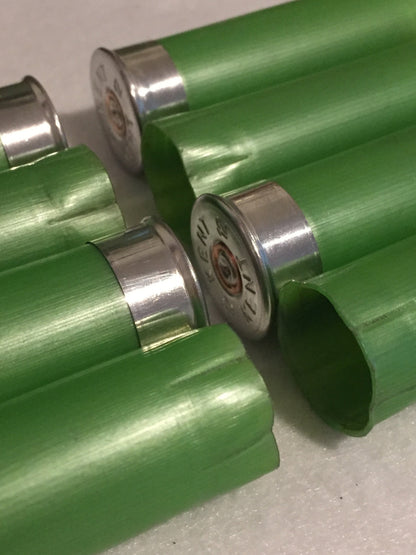 Close-up of empty lime green 12 gauge shotgun shells showing silver Kent headstamps and crimped open ends