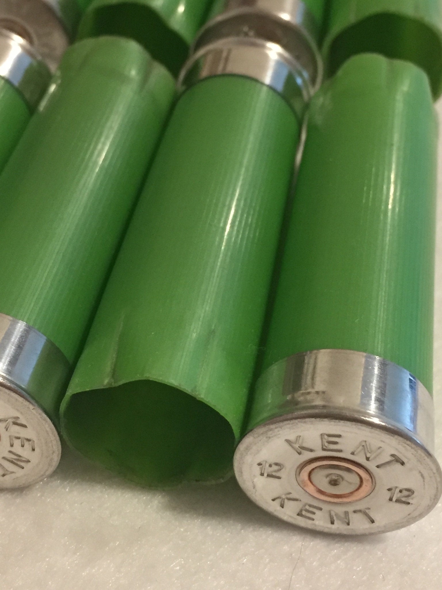 Close-up of empty lime green 12 gauge shotgun shells showing silver Kent headstamps