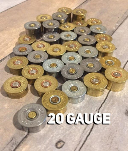 Arrangement of silver and gold tone 20 gauge spent headstamps on a light surface.
