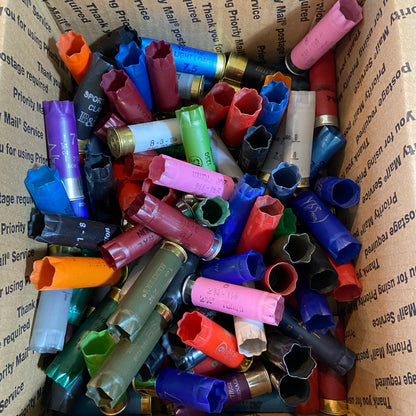 Mixed-color 12 gauge shotgun shell assortment including pink, blue, green, orange, red, and black hulls