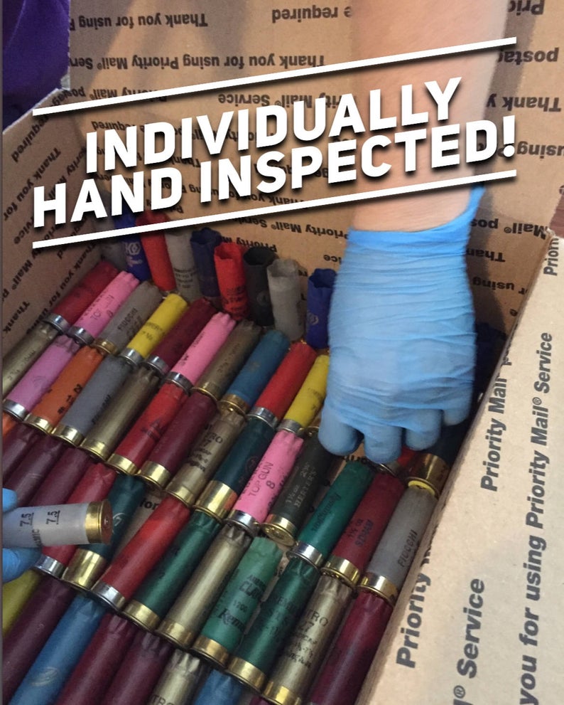Blue gloved hand holding a pile of mixed color empty 12 gauge shotgun shells with overlay text INDIVIDUALLY HAND INSPECTED.