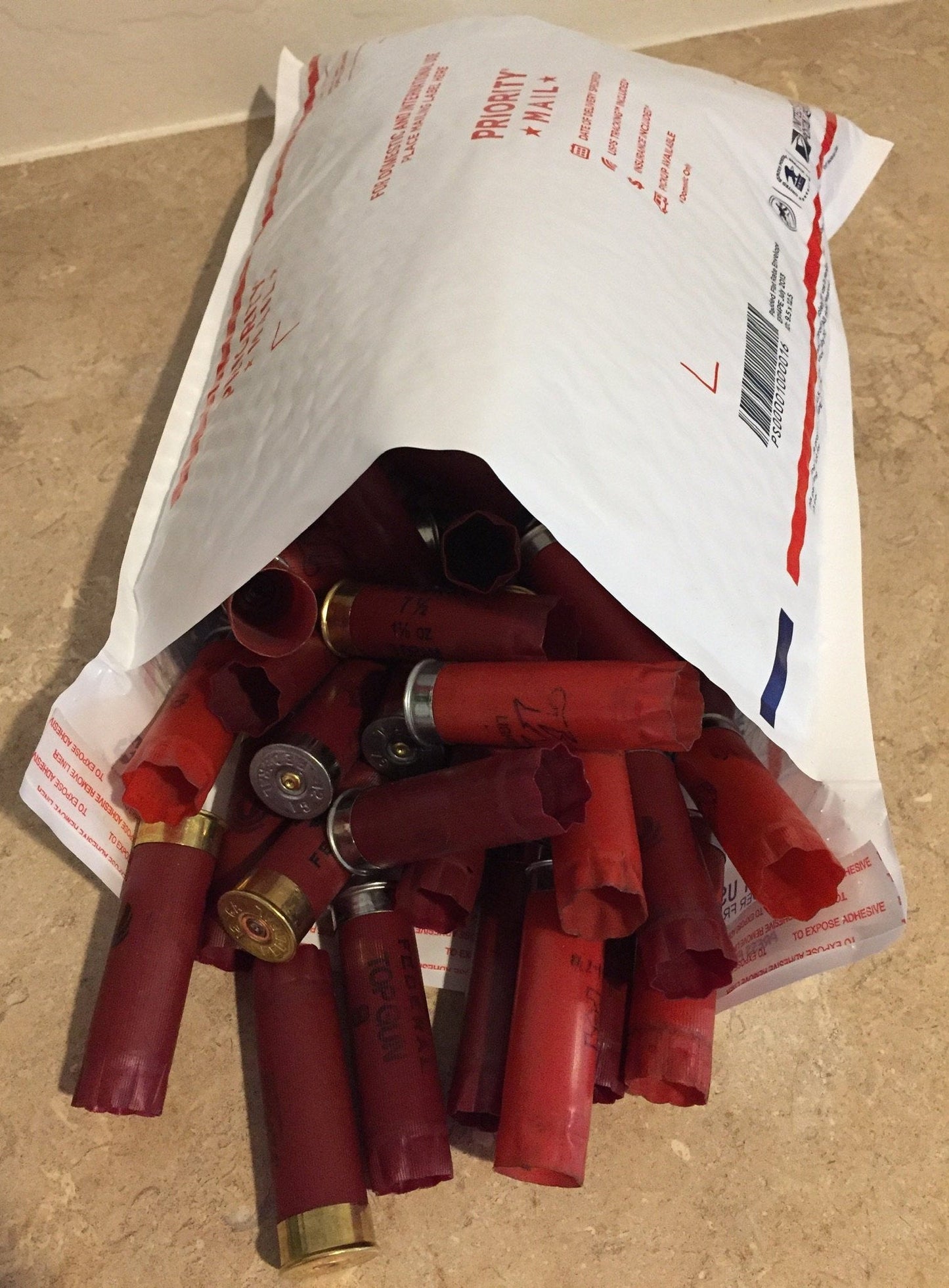 Mixed red 12 gauge shotgun shells in burgundy, maroon, and dark red tones, once-fired and uncleaned.