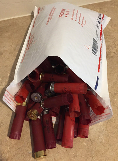 Mixed red 12 gauge shotgun shells in burgundy, maroon, and dark red tones, once-fired and uncleaned.