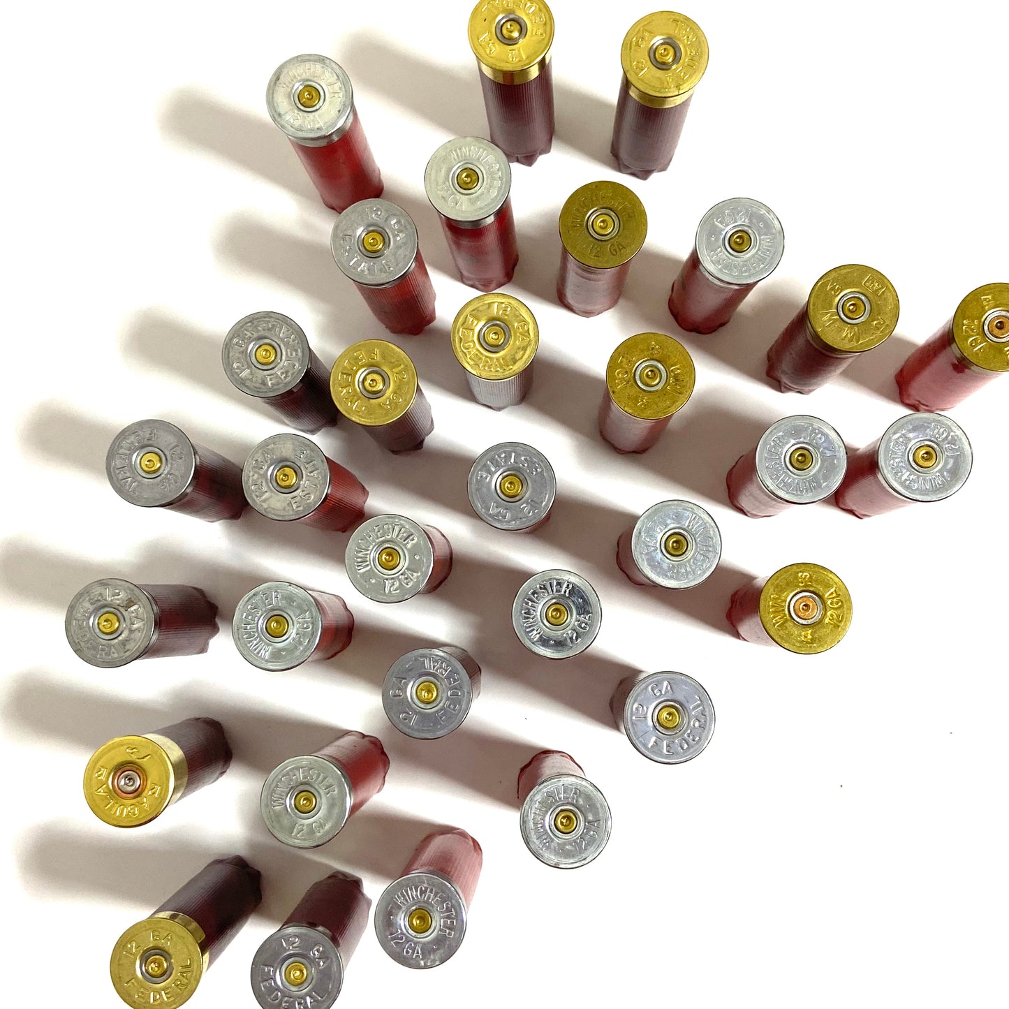 Many mixed red and burgundy spent shells standing upside down on a white surface, with silver and gold bases facing up.