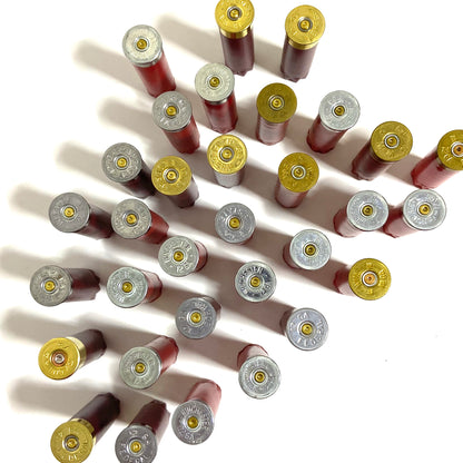 Many mixed red and burgundy spent shells standing upside down on a white surface, with silver and gold bases facing up.