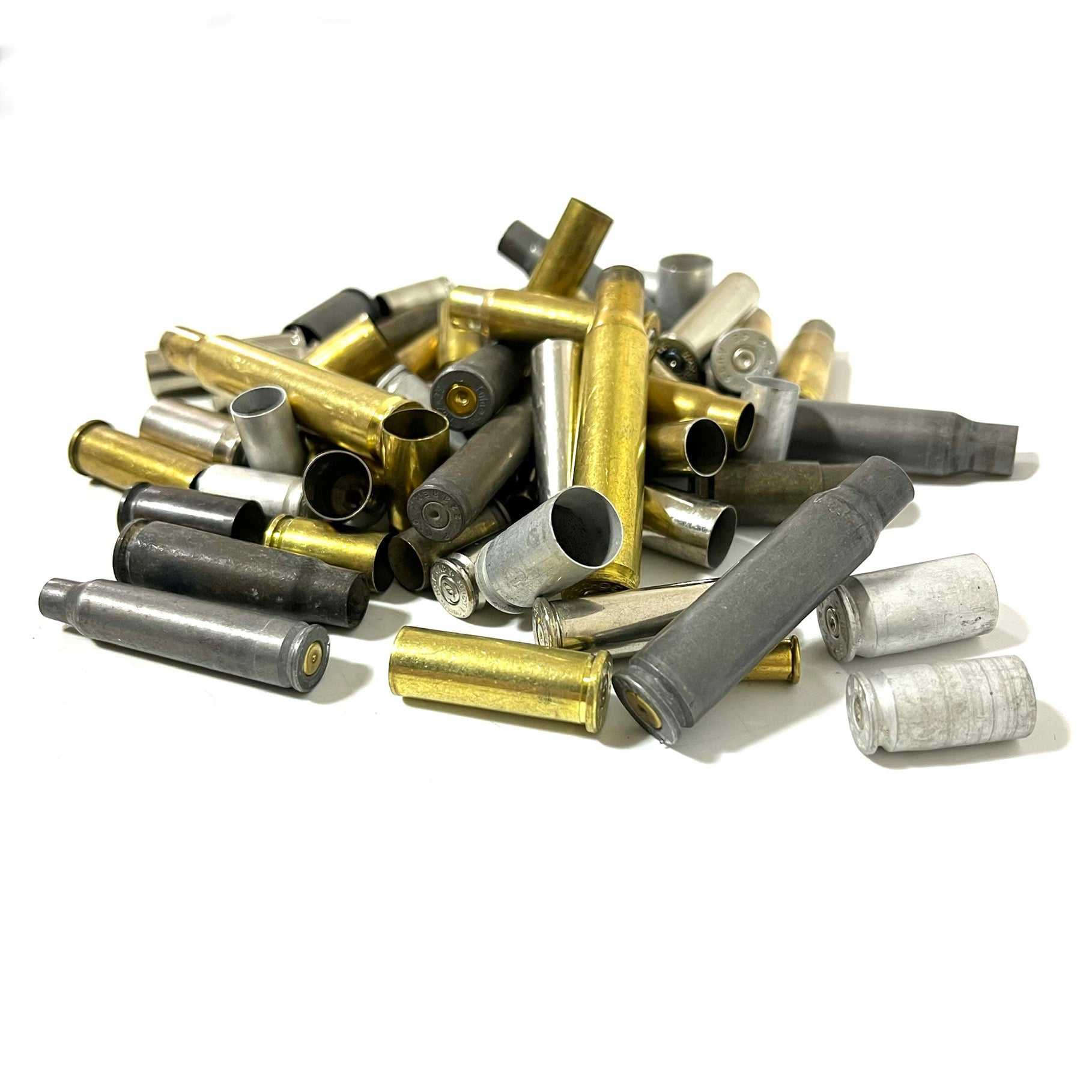 Dense pile of mixed spent bullet casings featuring dark steel, yellow brass, and silver nickel cases on a white background.