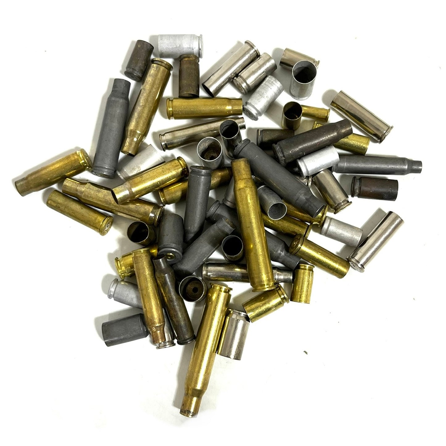 Bulk pile of mixed spent casings in brass, dark steel, and silver nickel on a white background, top view.