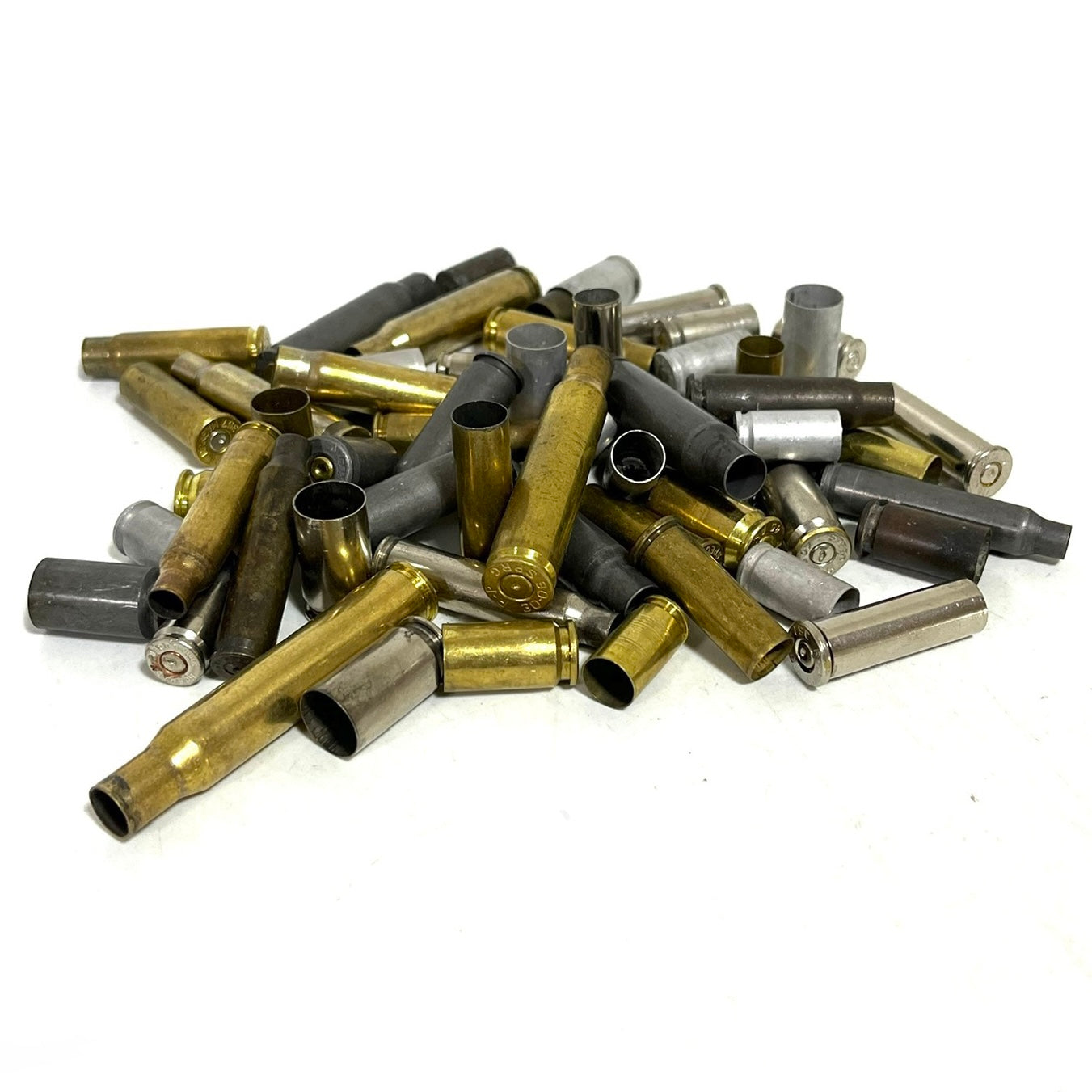Bulk heap of mixed spent shells in brass, nickel, and dark steel on a white background.