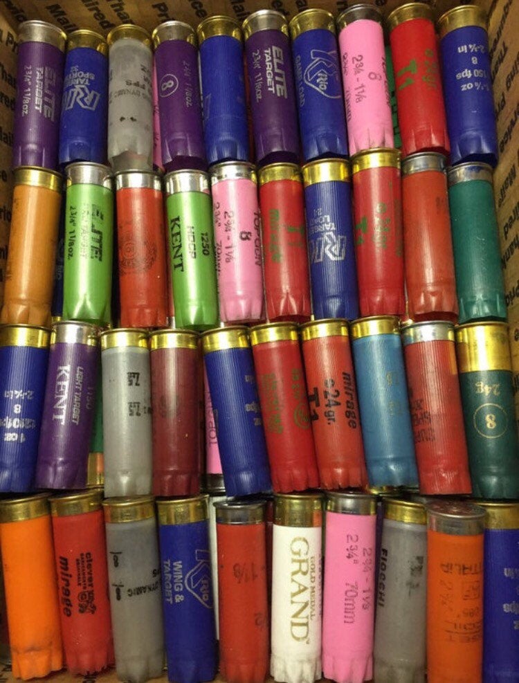 Empty 12 gauge shotgun hulls arranged in rows to show the range of assorted colors
