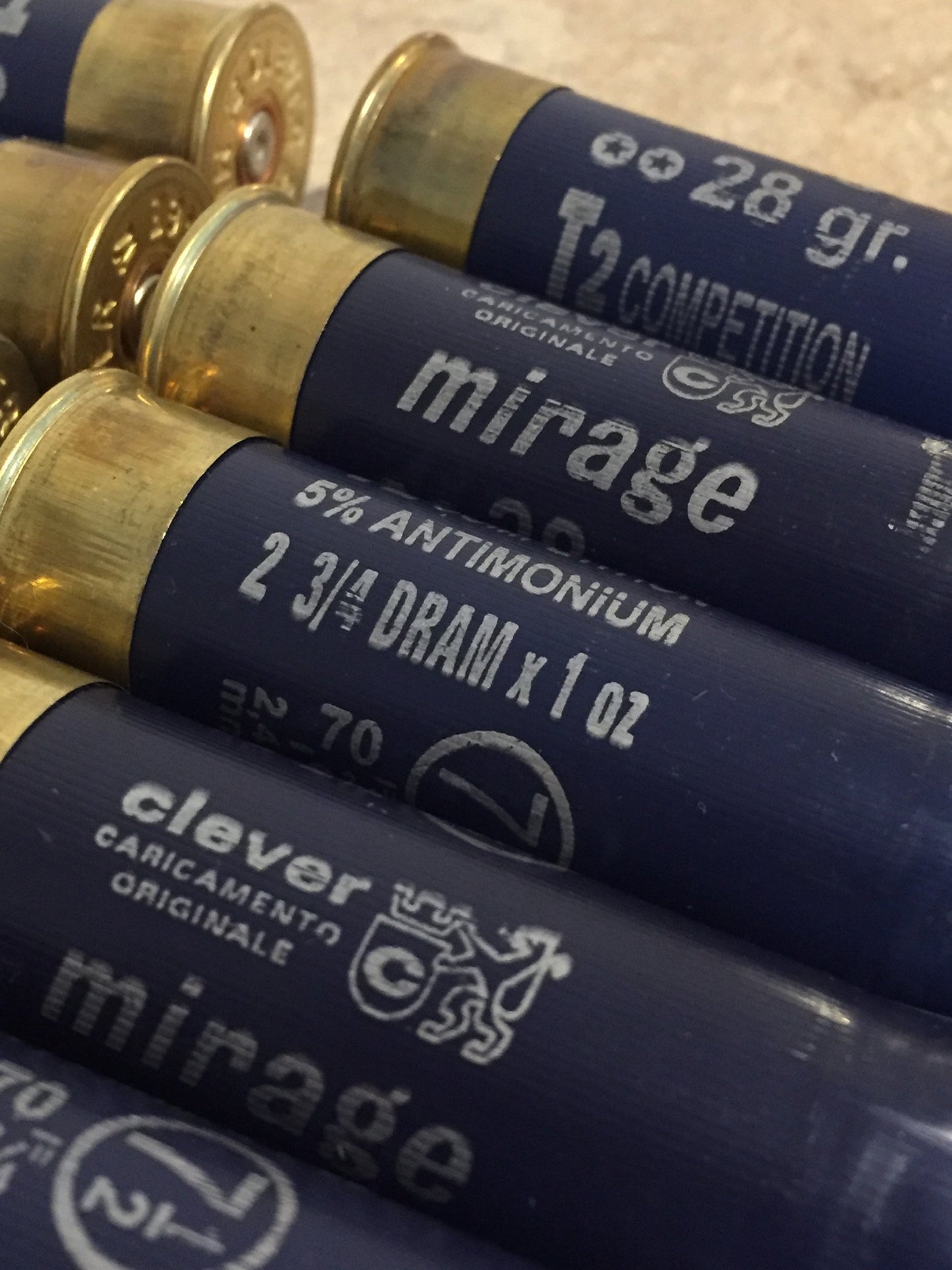 Empty navy blue 12 gauge Clever Mirage shotgun shells with brass bases showing printed markings on a stone surface