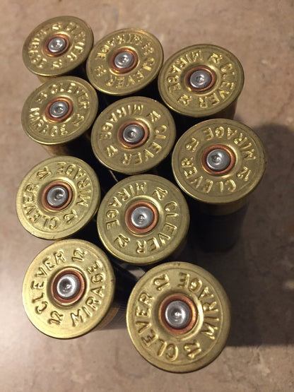 10 navy blue shotgun shell gold brass bases viewed from above, Clever Mirage 12 headstamps in cluster on tile
