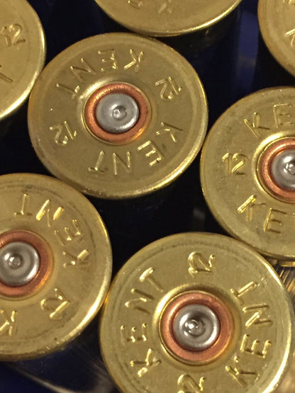 Close-up of gold Kent 12 gauge headstamps on navy blue shotgun shells