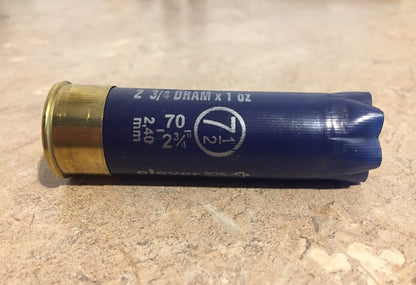 Single empty navy blue 12 gauge Clever Mirage shotgun shell with brass base on a stone surface